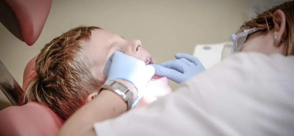 Dentista examinando os dentes de um menino deitado na cadeira