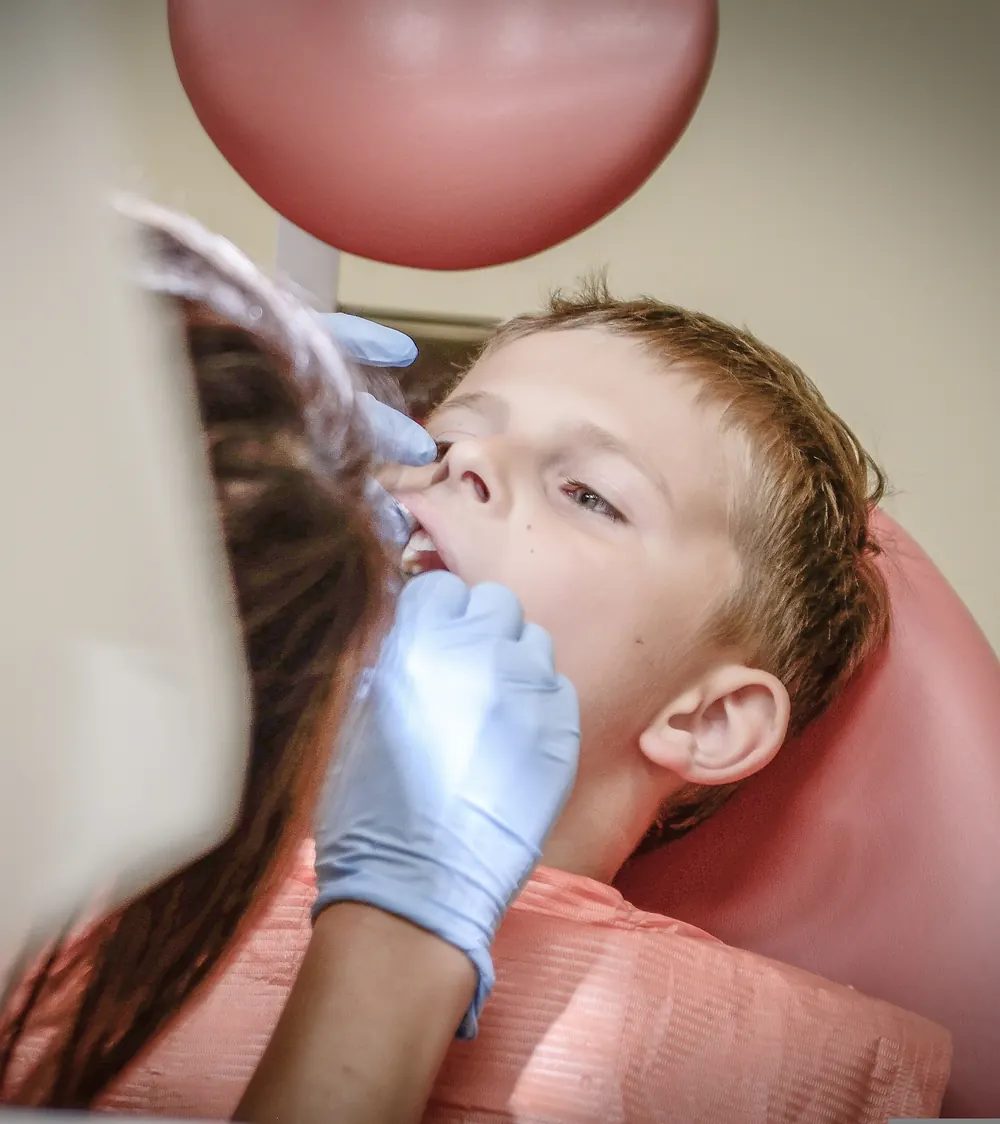 Mão de luva examinando os dentes de um menino, foto de exemplo